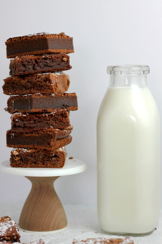 A glass milk bottle beside a tower of brownies on a small pedestal 
