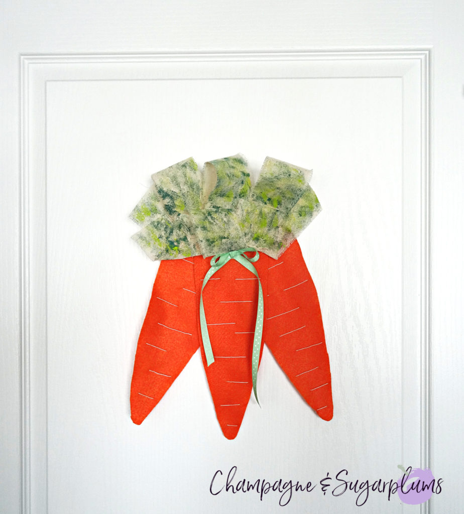 Completed carrot door decoration hanging on a white door by Champagne and Sugarplums 