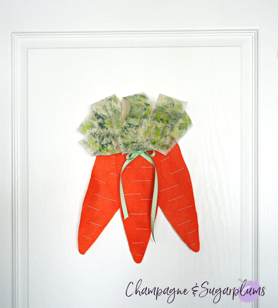 Completed carrot door decoration hanging on a white door by Champagne and Sugarplums