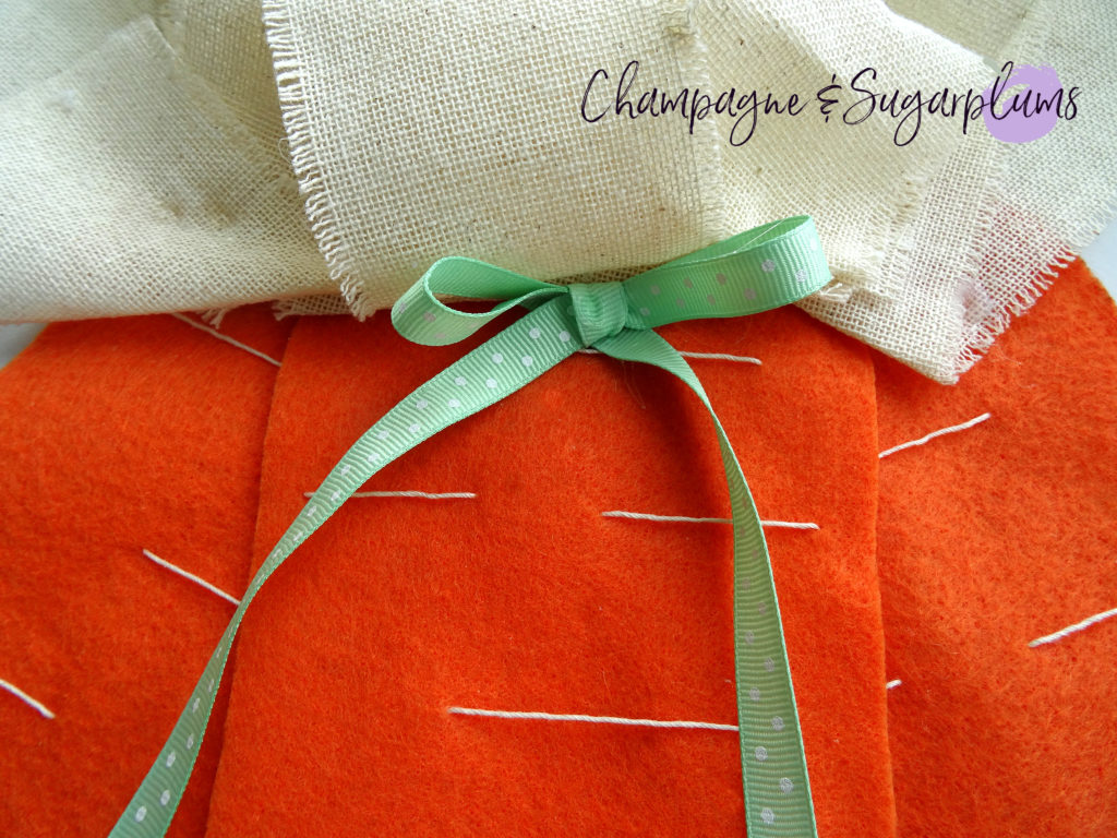 A small green ribbon bow attached to the top of the felt carrots by Champagne and Sugarplums 