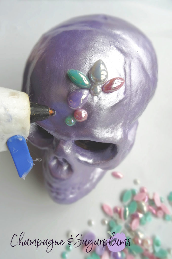 Gluing gems onto a lilac skull by Champagne and Sugarplums 