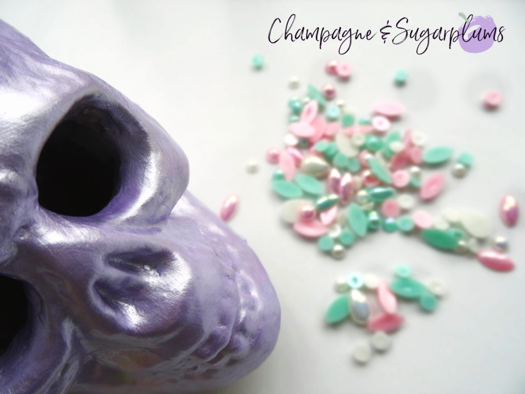 A lilac skull on a white background with teal, pink and white gems by Champagne and Sugarplums 