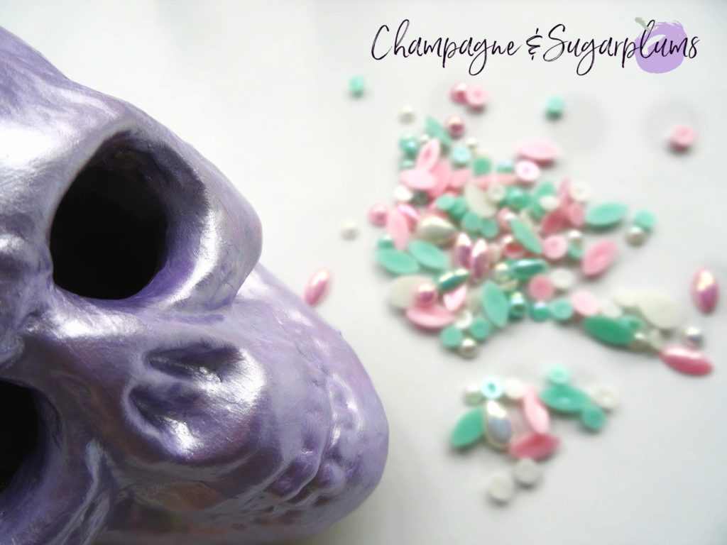 A lilac skull on a white background with teal, pink and white gems by Champagne and Sugarplums