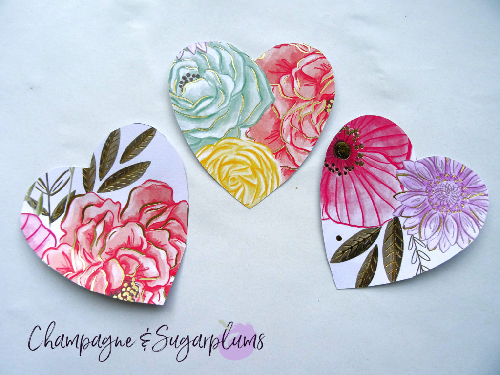 Three hearts cut from floral paper on a white background by Champagne and Sugarplums