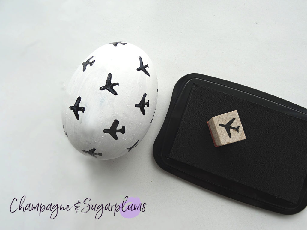 An egg being stamped with mini airplanes on a white background by Champagne and Sugarplums
