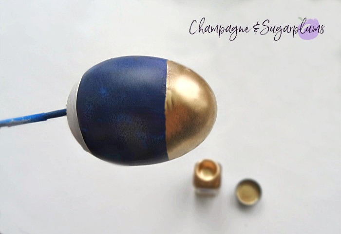 An egg being half painted with gold by Champagne and Sugarplums