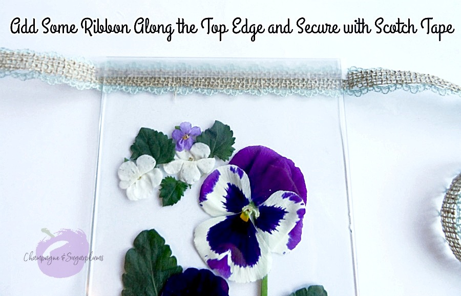 Ribbon being secured to the top edge of two sheets of glass holding pressed flowers by Champagne and Sugarplums
