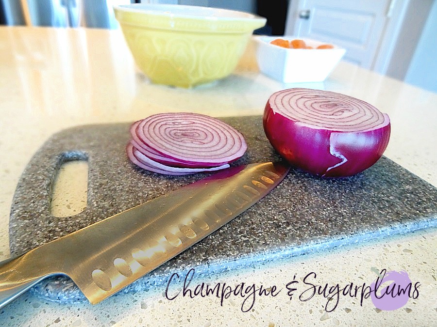 Cutting up an onion on a white counter by Champagne and Sugarplums