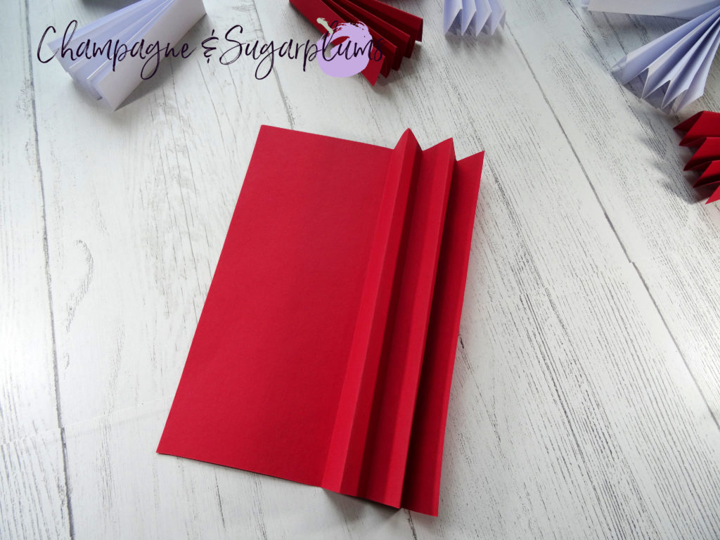 Red paper being folded it an accordion shape by Champagne and Sugarplums