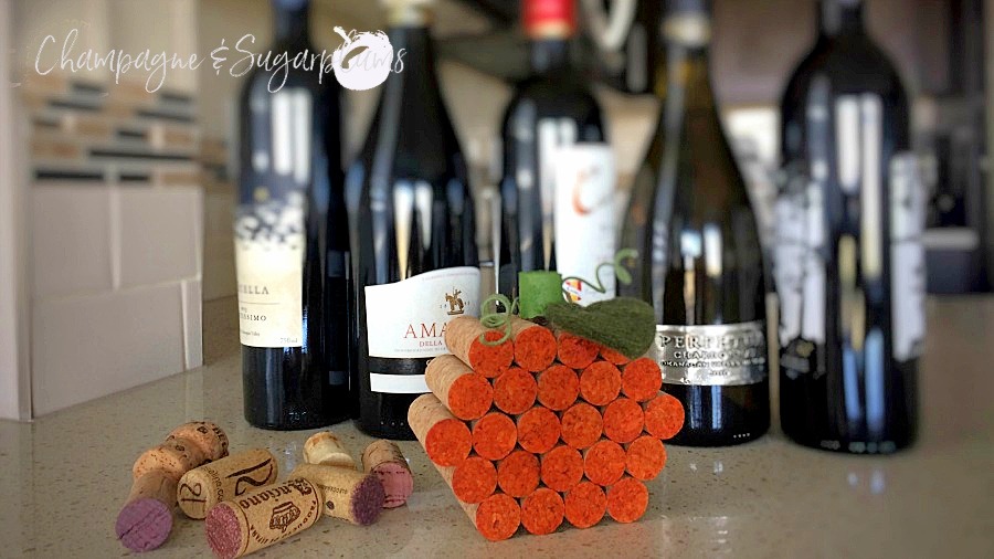 jack-o-lantern cork pumpkin on a counter in front of wine bottles by Champagne and Sugarplums