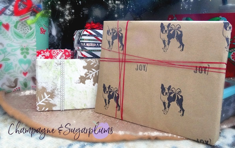 A collection of gifts wrapped in DIY holiday wrapping paper under a tree by Champagne and Sugarplums