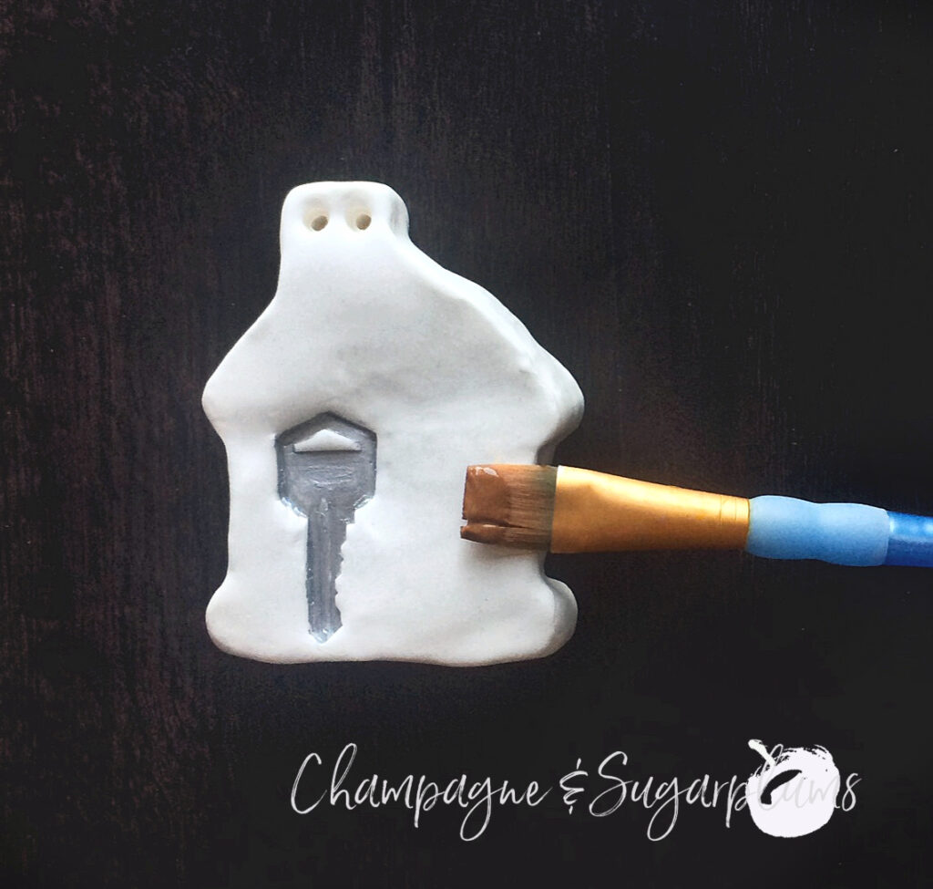 Painting a key stamp silver on a Gingerbread house ornament by Champagne and Sugarplums