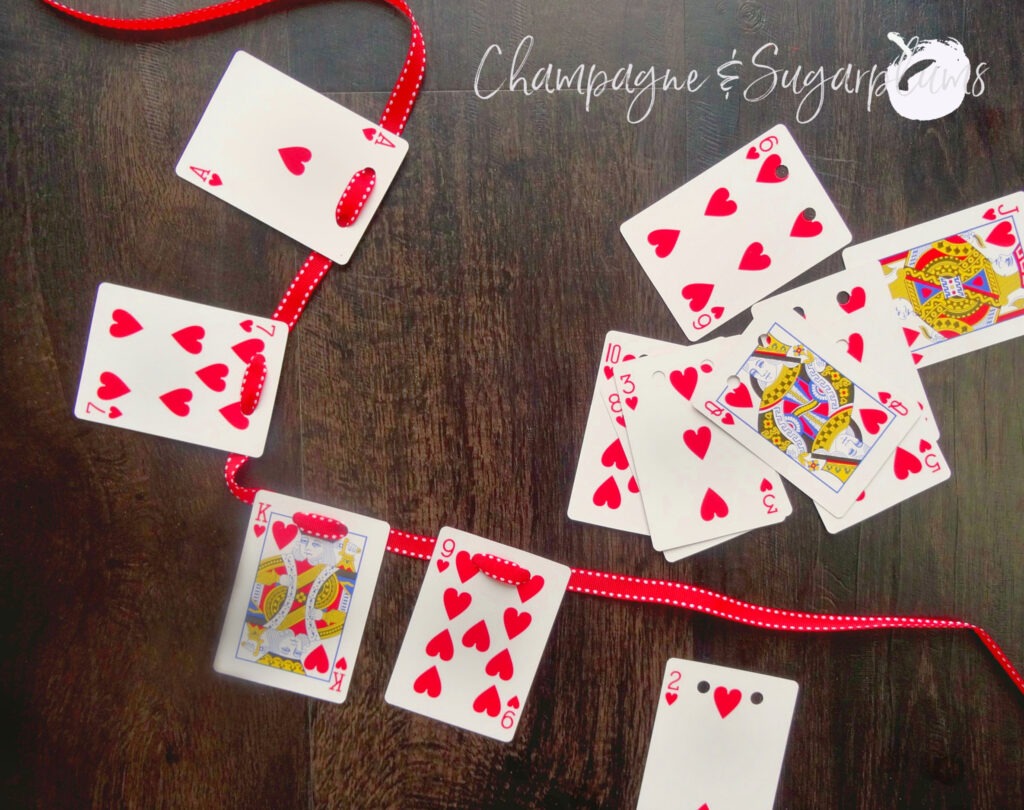 Playing cards being threaded onto ribbon by Champagne and Sugarplums