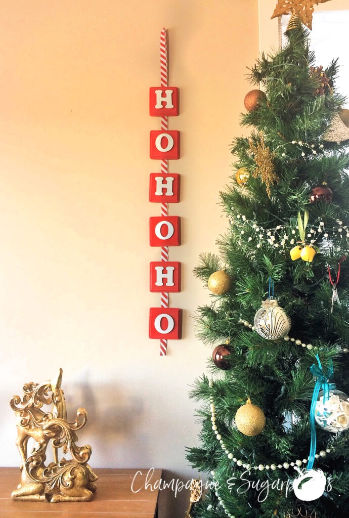 Christmas banner hanging on a wall beside a decorated tree by Champagne and Sugarplums