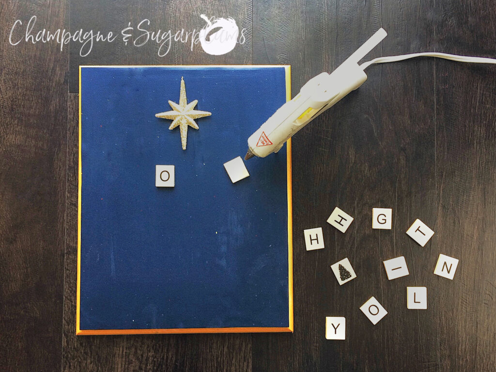 Gluing letter tiles to wood plank with a gold star by Champagne and Sugarplums