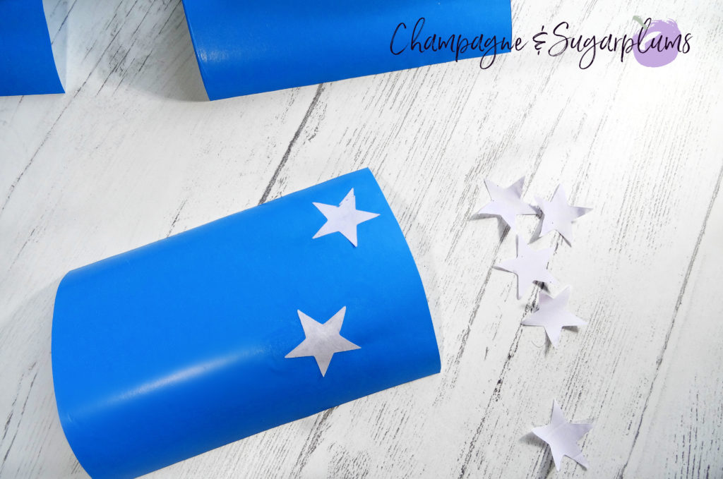 Adding star stickers to blue paper by Champagne and Sugarplums