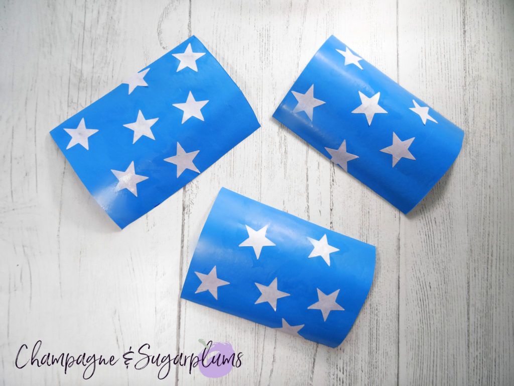 Adding star stickers to blue paper by Champagne and Sugarplums