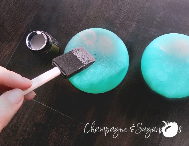 Foam brush applying gilding medium to teal ornaments by Champagne and Sugarplums