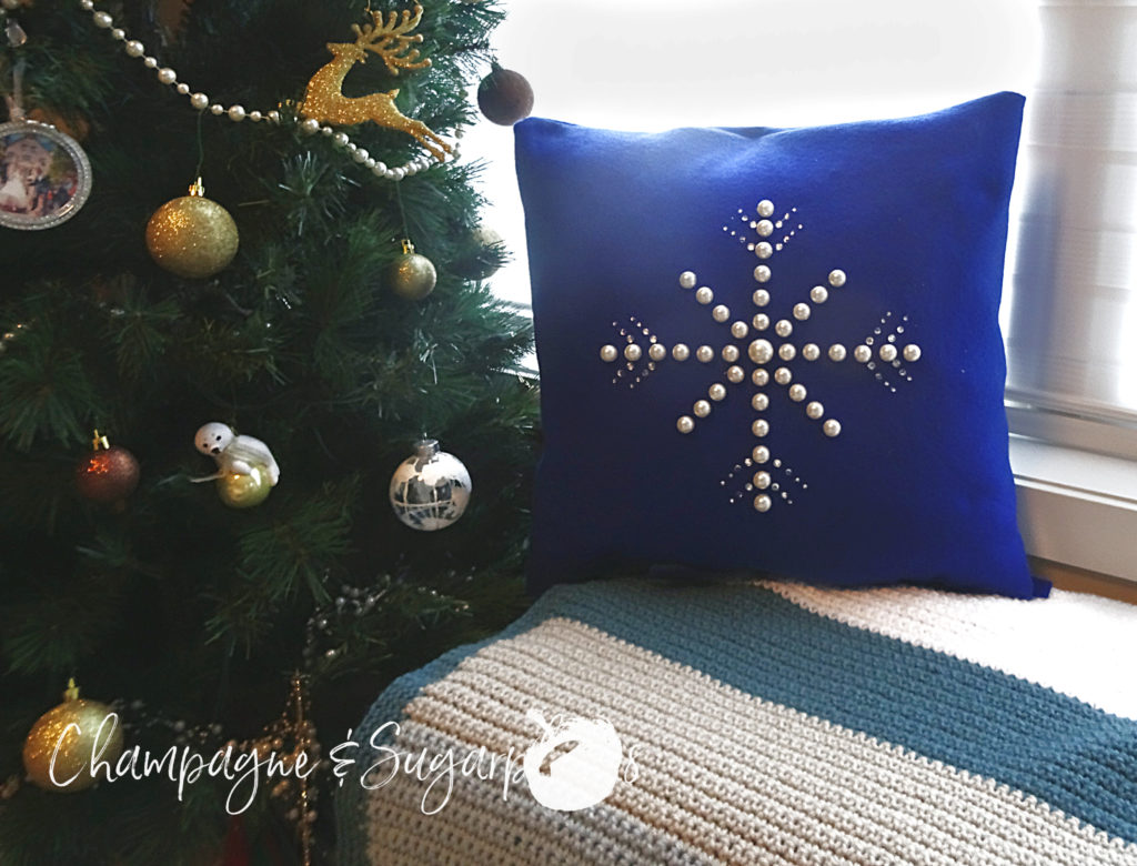 Snowflake pillow cover on a bench beside a Christmas tree by Champagne and Sugarplums