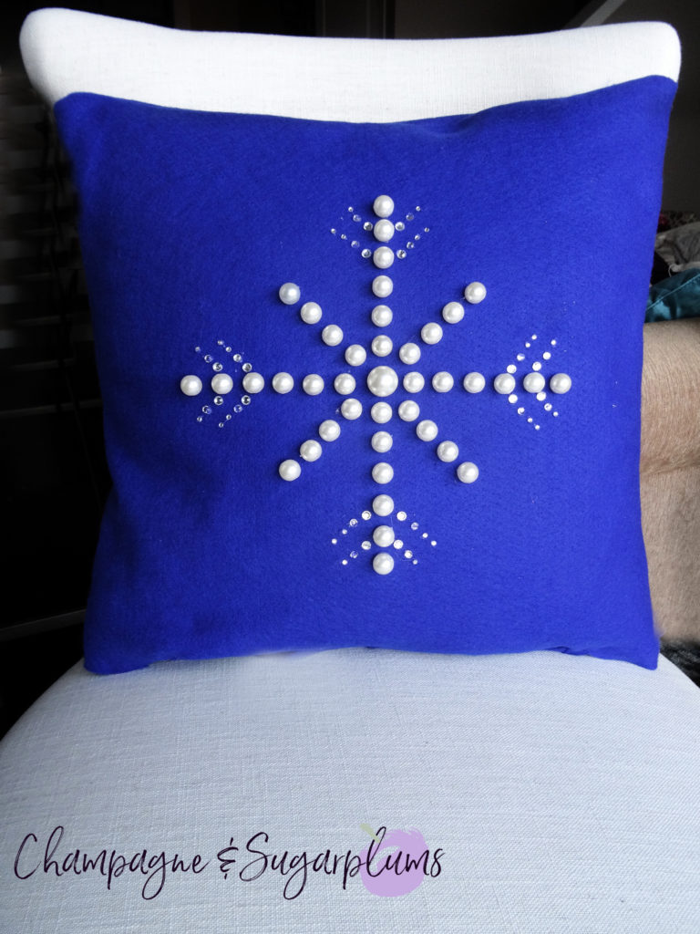 Snowflake pillow cover on a white chair by Champagne and Sugarplums