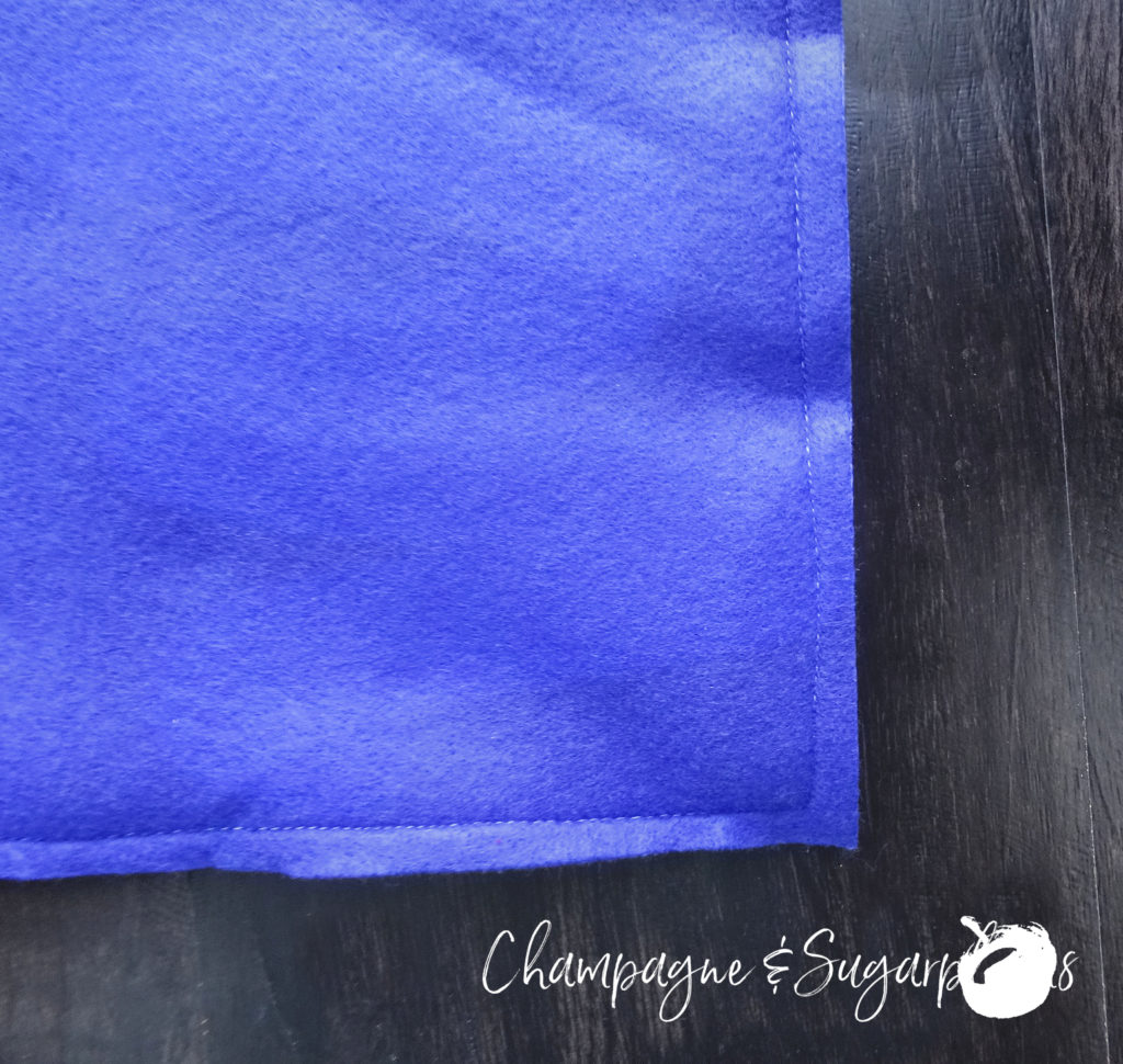 The corner of two pieces of royal blue felt sewn together by Champagne and Sugarplums