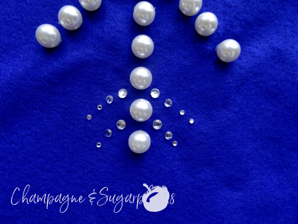 Clear gems glued to royal blue felt next to pearl beads by Champagne and Sugarplums
