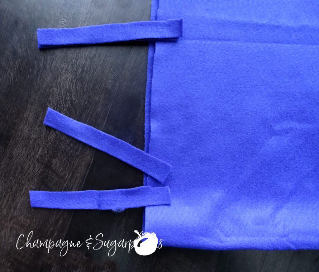 Strips of royal blue felt being sewn to the a pillow cover by Champagne and Sugarplums