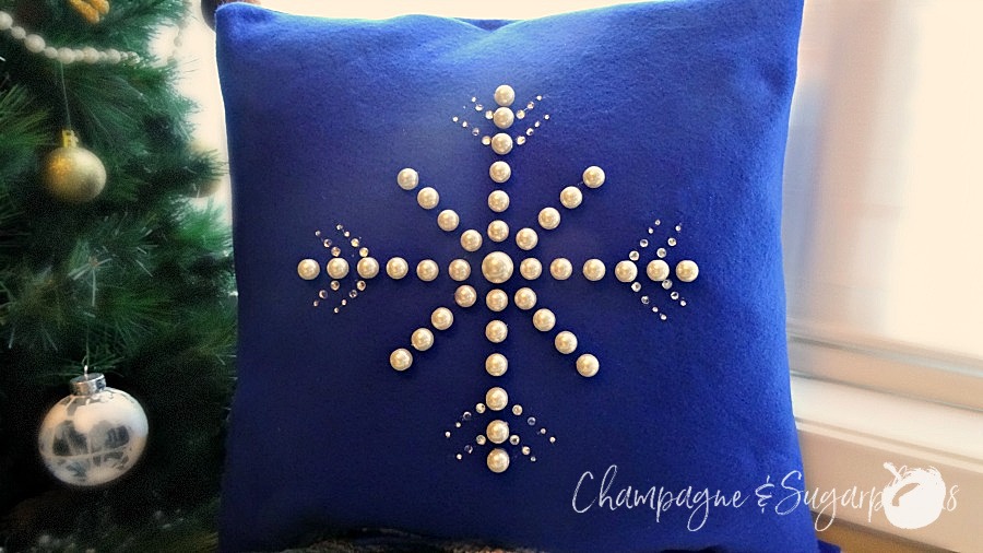 Snowflake pillow cover on a bench beside a Christmas tree by Champagne and Sugarplums