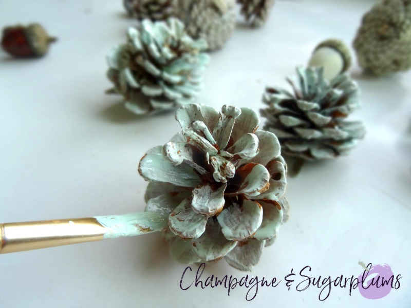 Pinecone being painted blue by Champagne and Sugarplums