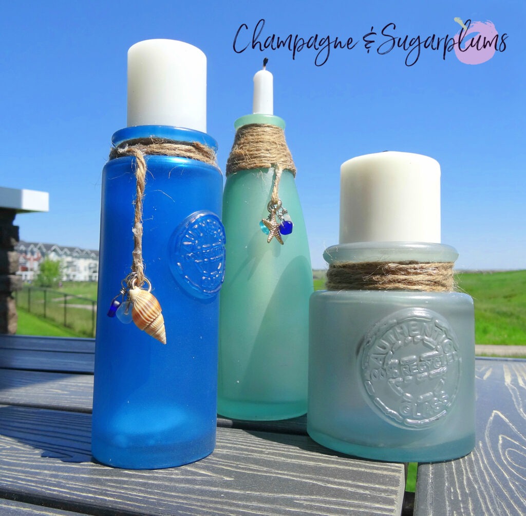 Sea glass bottles on a table outside on a sunny day by Champagne and Sugarplums