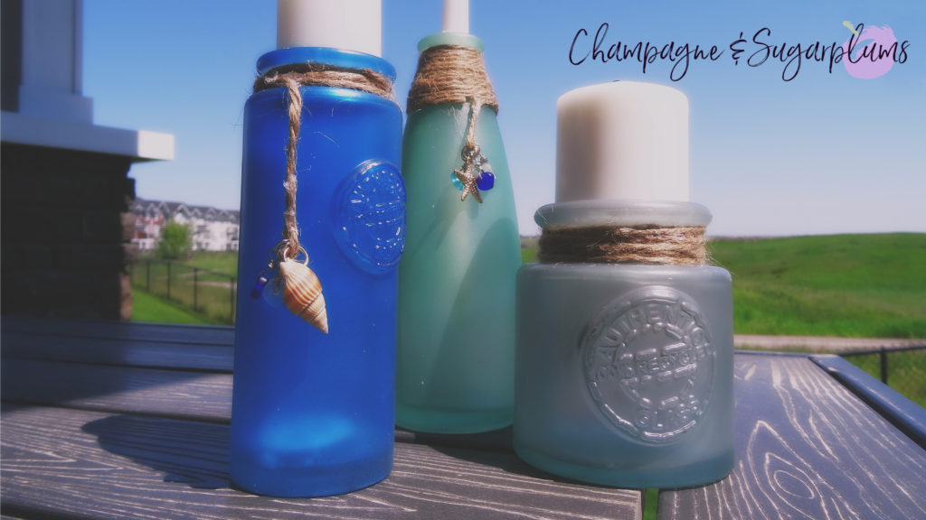 Sea glass bottles on a table outside on a sunny day by Champagne and Sugarplums