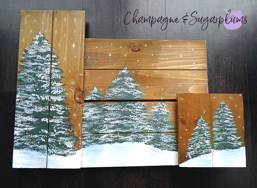 Painted holiday trees with glitter twinkle lights on wood planks on a dark background by Champagne and Sugarplums