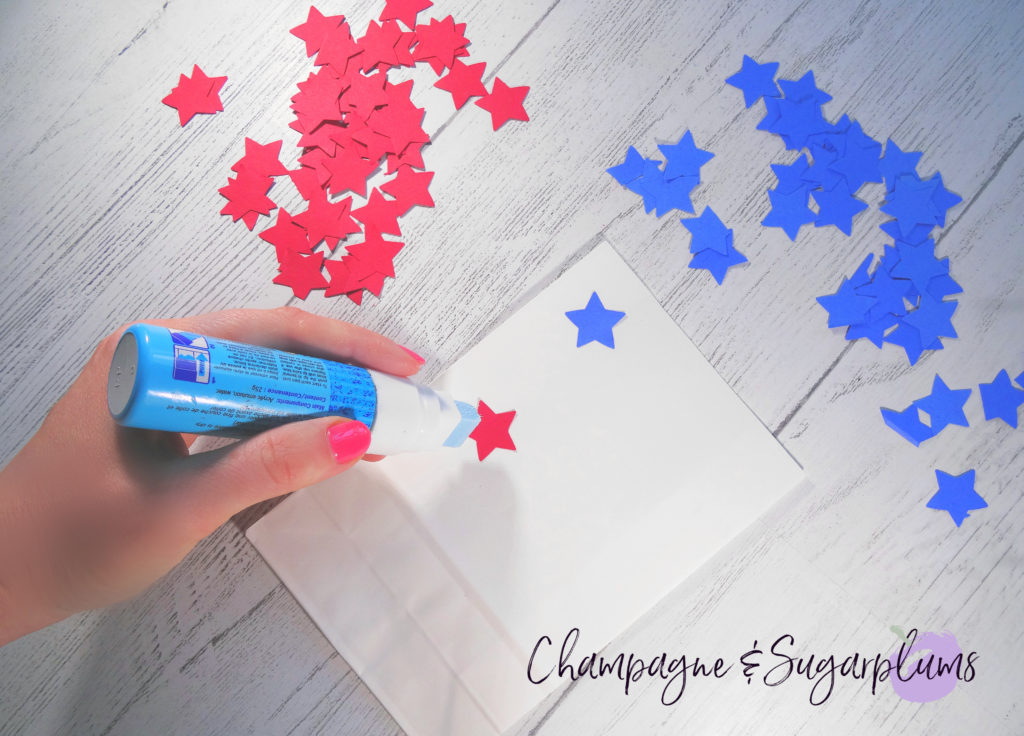 Gluing red and blue stars onto white paper bags by Champagne and Sugarplums