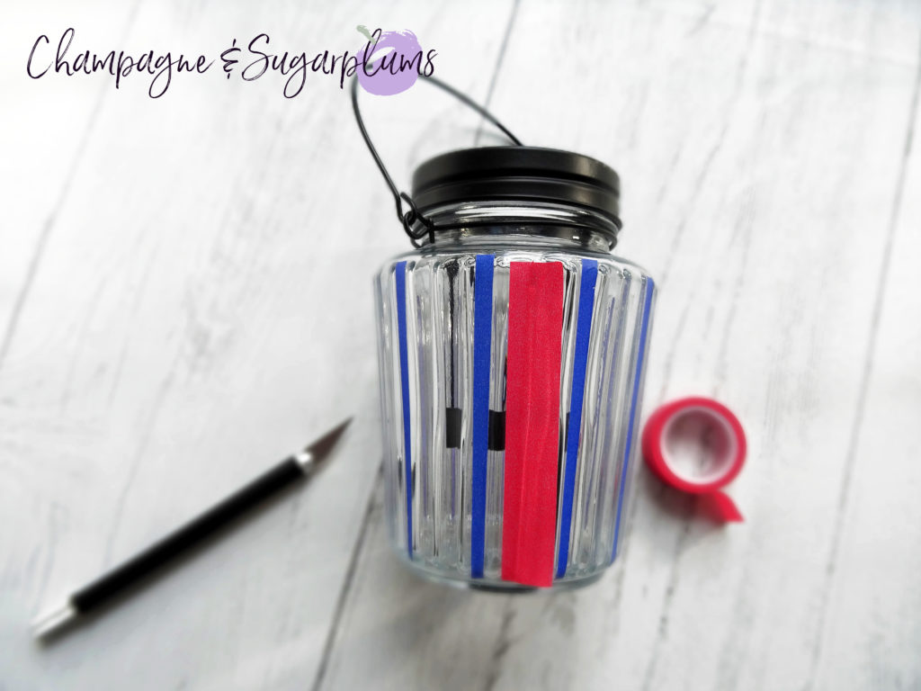 Adding red tape to a glass candle jar by Champagne and Sugarplums