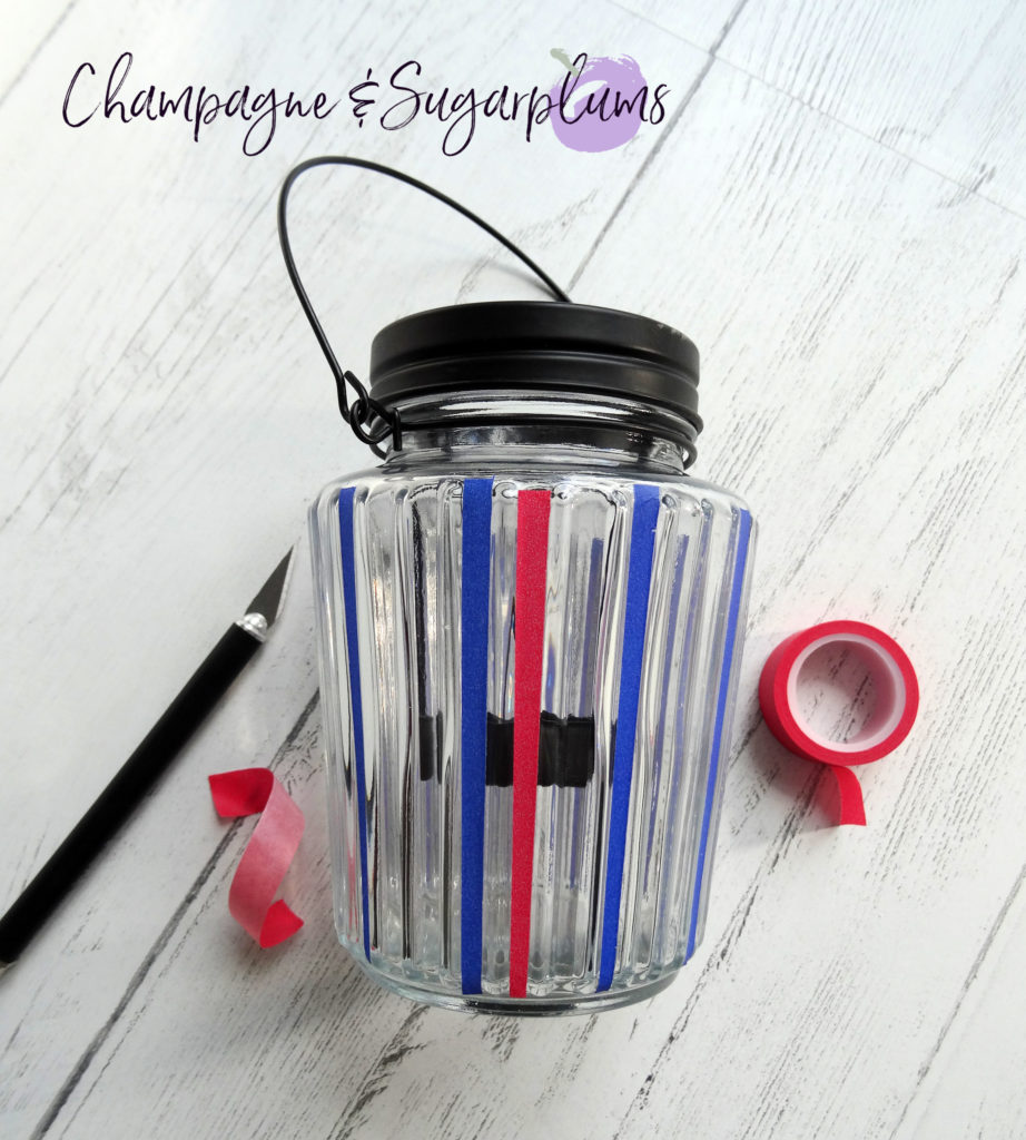 Adding red tape to a glass candle jar by Champagne and Sugarplums