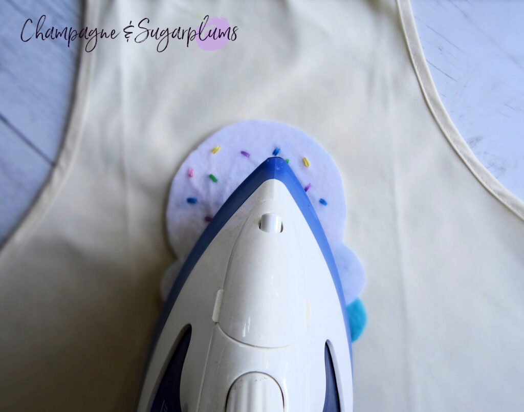 Ironing felt ice cream shapes onto white apron by Champagne and Sugarplums