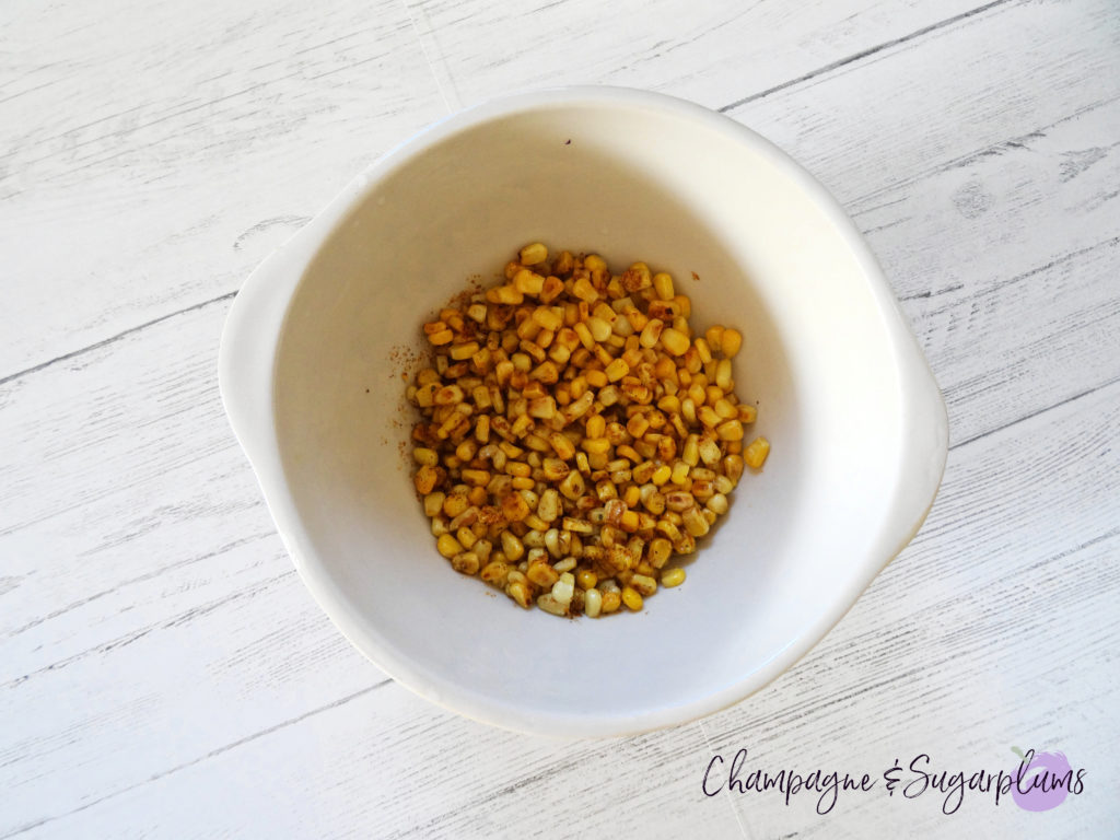 Seasoned cooked corn in a white bowl by Champagne and Sugarplums