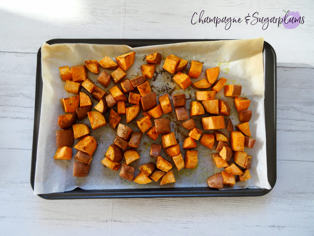 Roasted sweet potatoes on a sheet pan by Champagne and Sugarplums