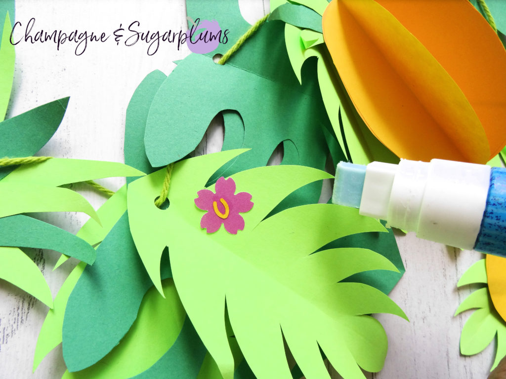 Gluing pink flowers onto green paper leaves by Champagne and Sugarplums