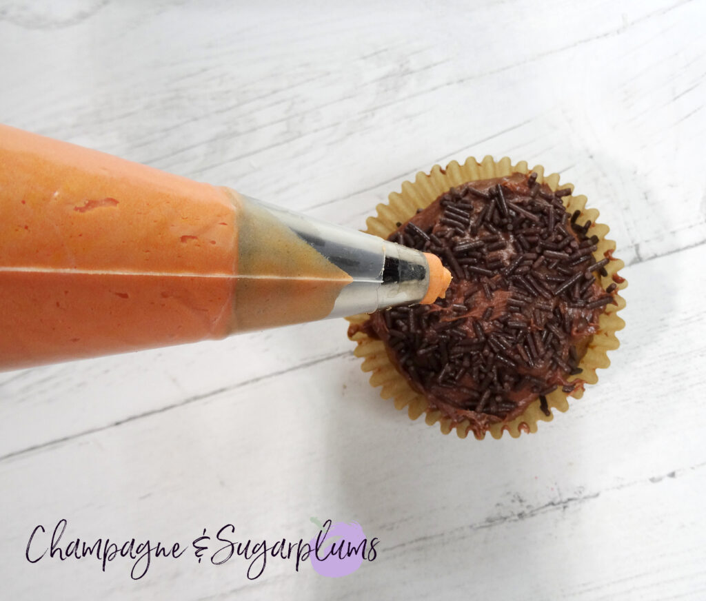Piping orange icing onto a cupcake on a white background by Champagne and Sugarplums