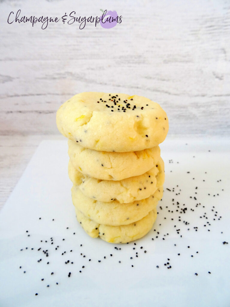 Lemon Poppy Seed Cookies stacked on a white plate by Champagne and Sugarplums