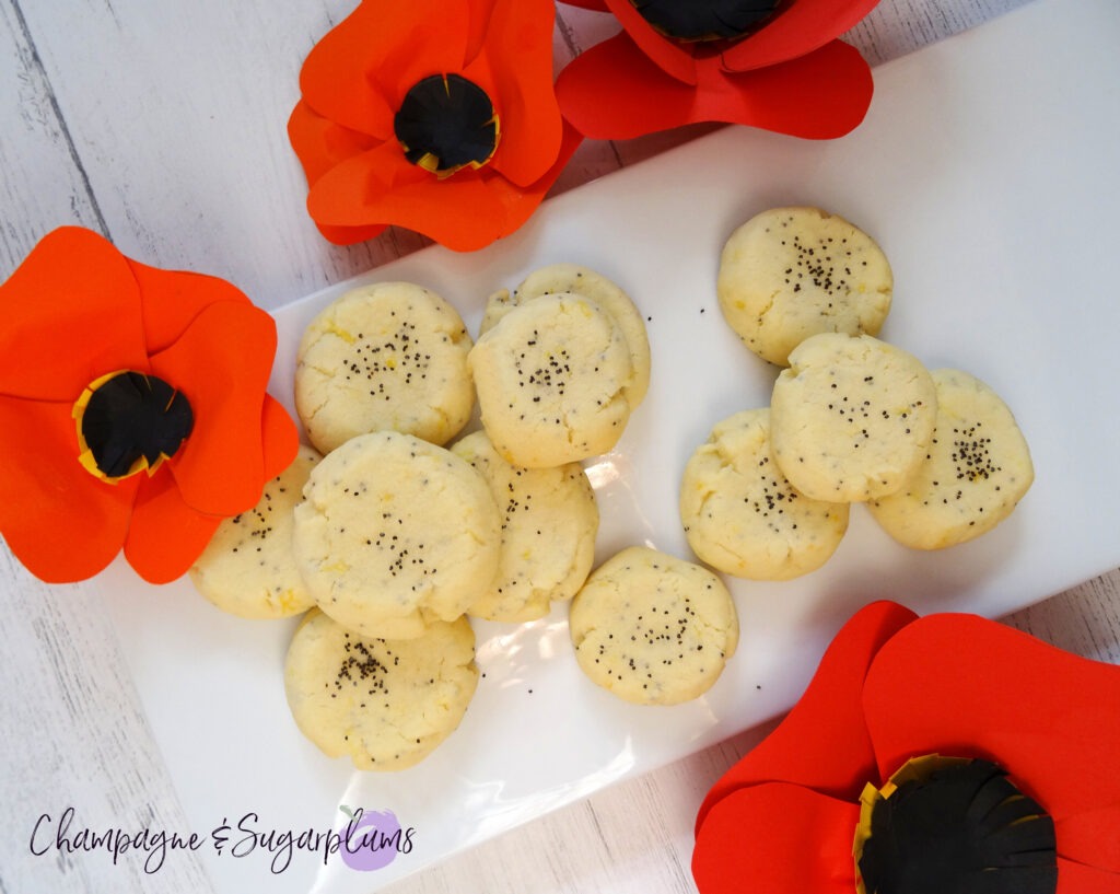 Lemon Poppy Seed Cookies on a white plate with red paper poppies by Champagne and Sugarplums