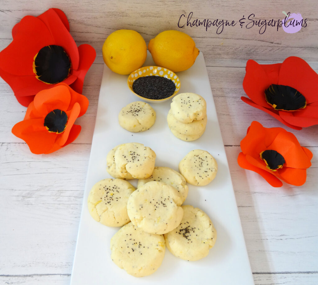 Lemon Poppy Seed Cookies on a white plate with red paper poppies, lemons and poppy seeds by Champagne and Sugarplums