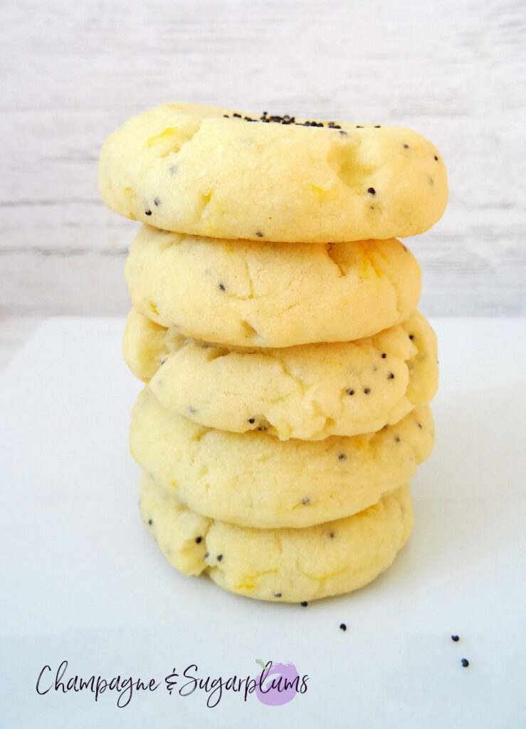 Lemon Poppy Seed Cookies stacked on a white plate by Champagne and Sugarplums