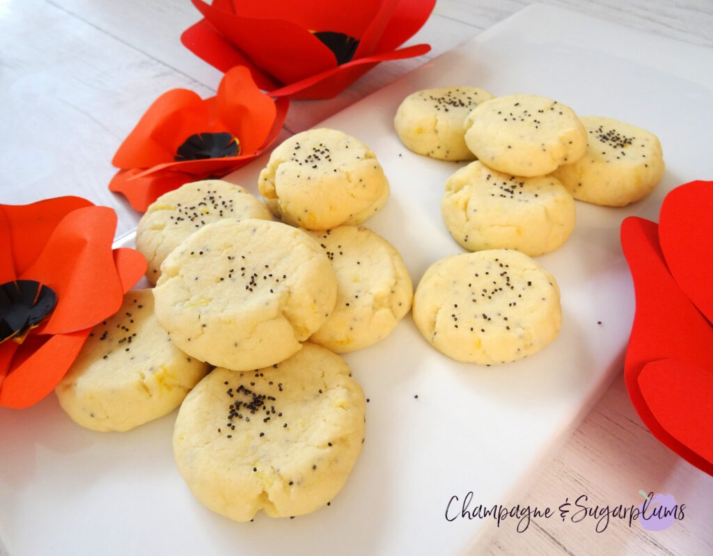 Lemon Poppy Seed Cookies on a white plate with red paper poppies by Champagne and Sugarplums