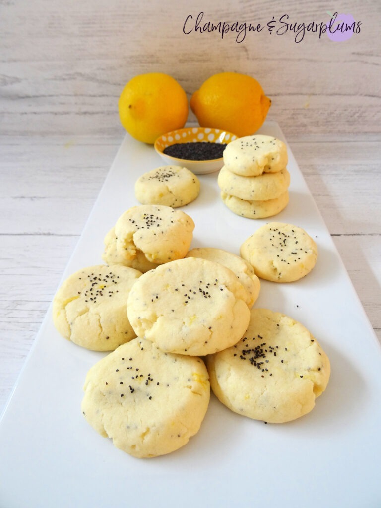 Lemon Poppy Seed Cookies on a white plate with lemons and poppy seeds by Champagne and Sugarplums