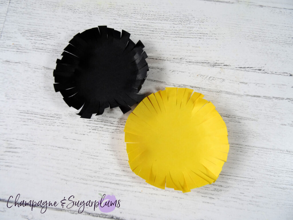 One black and one yellow fringed circle side by side on a white background by Champagne and Sugarplums