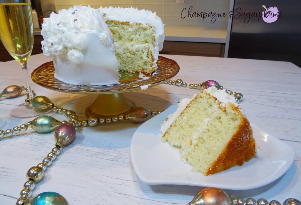 Champagne Cake sliced on white pate with a decorative stand with champagne flutes and garland by Champagne and Sugarplums