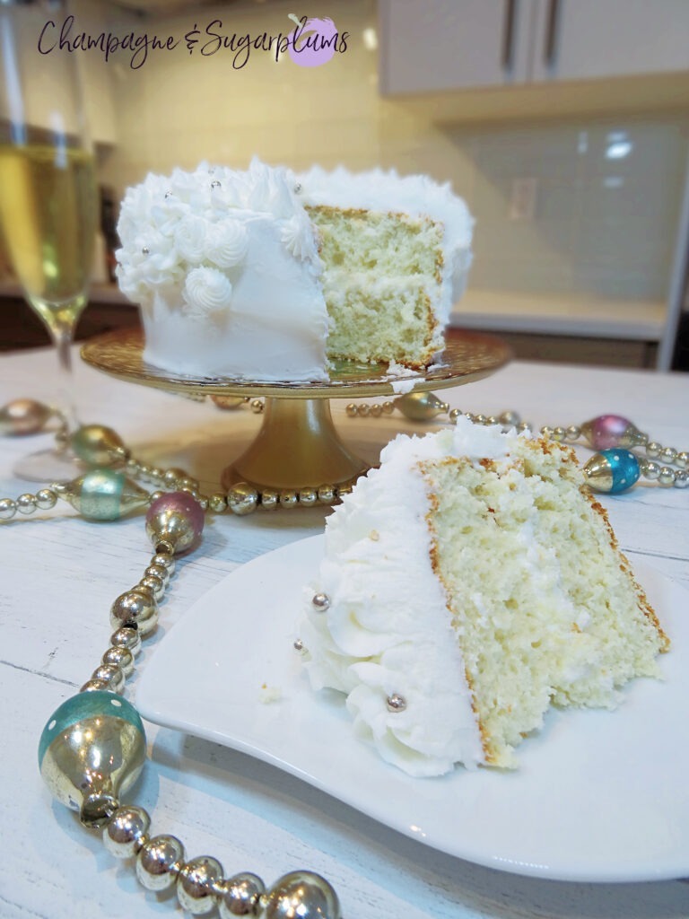 Champagne Cake sliced on white pate with a decorative stand with champagne flutes and garland by Champagne and Sugarplums