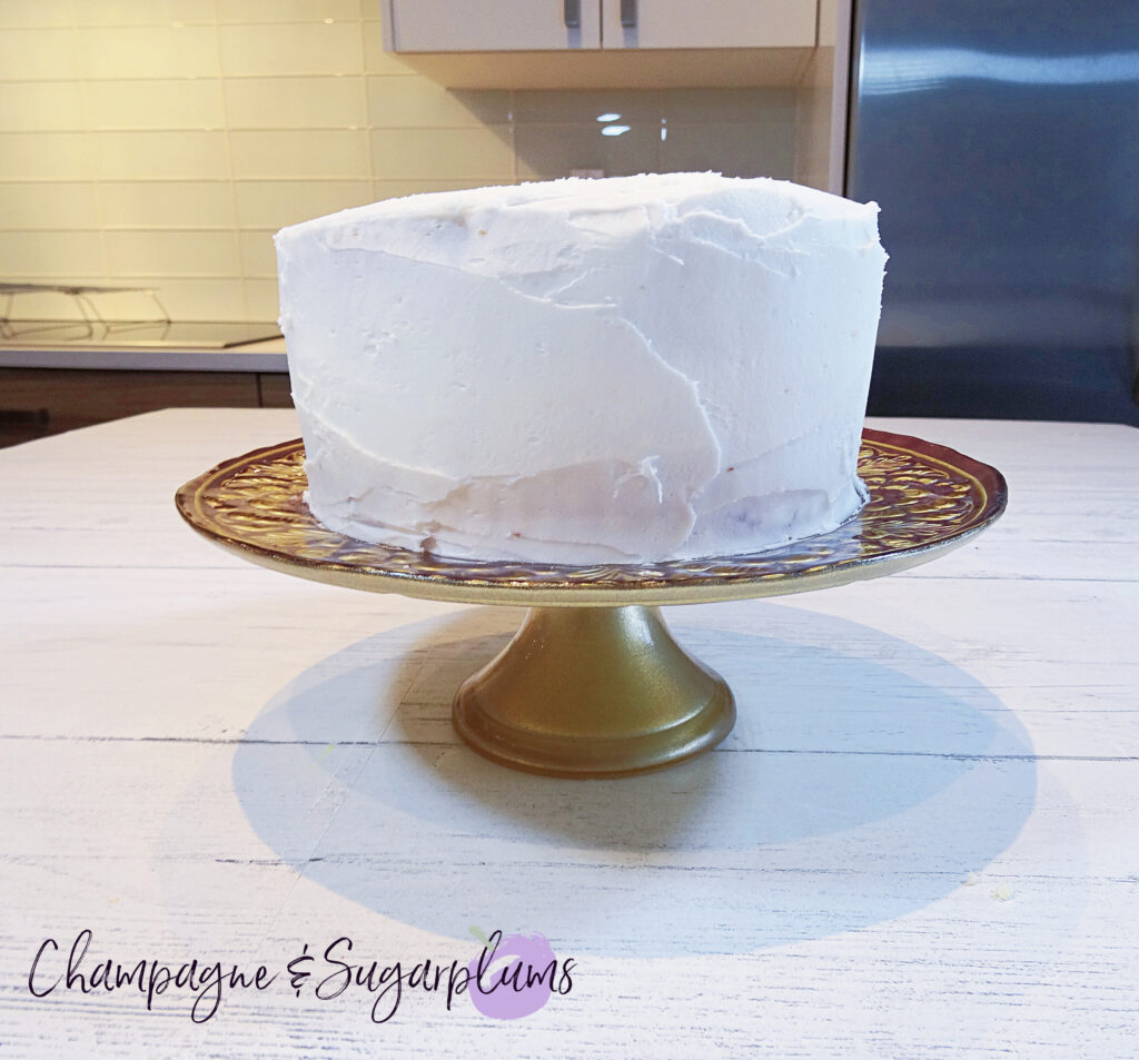 Icing a cake with white icing by Champagne and Sugarplums
